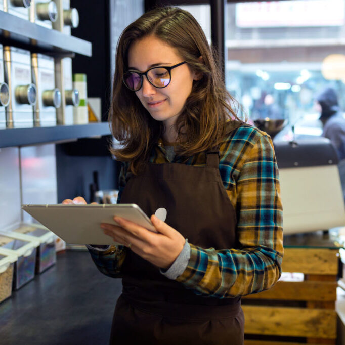 Portrait of beautiful young saleswoman doing inventory in a retail store selling coffee.